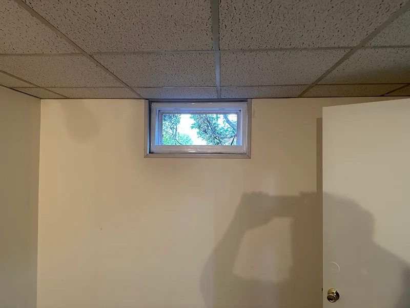 Basement window with a rotting metal frame